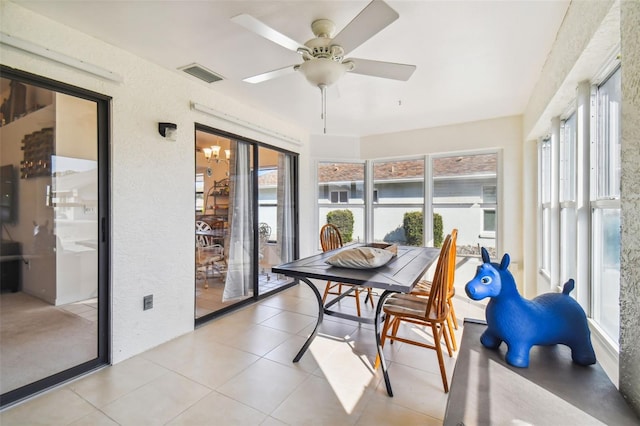 sunroom featuring ceiling fan with notable chandelier