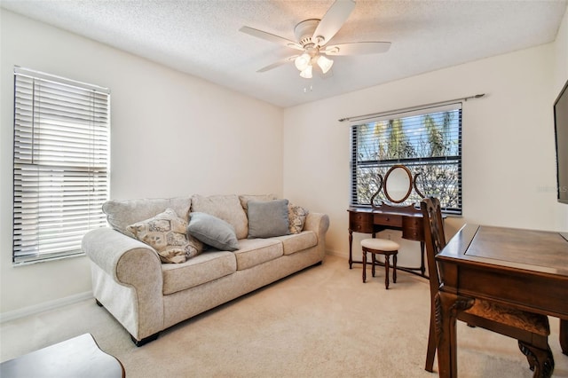 living room with a textured ceiling, light colored carpet, and ceiling fan