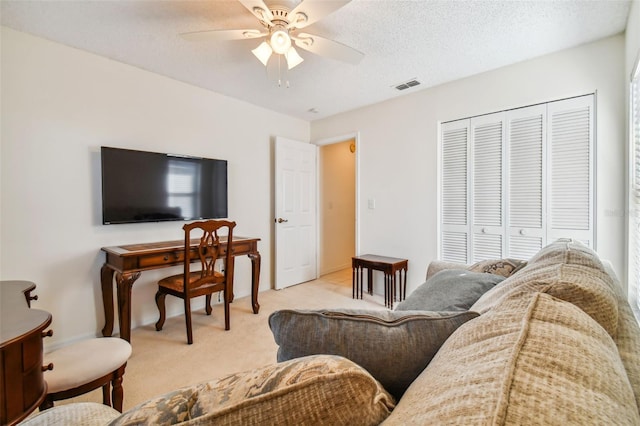 living room with a textured ceiling, light colored carpet, and ceiling fan