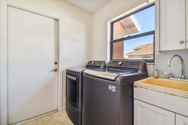 laundry area featuring light tile flooring, washing machine and clothes dryer, and cabinets