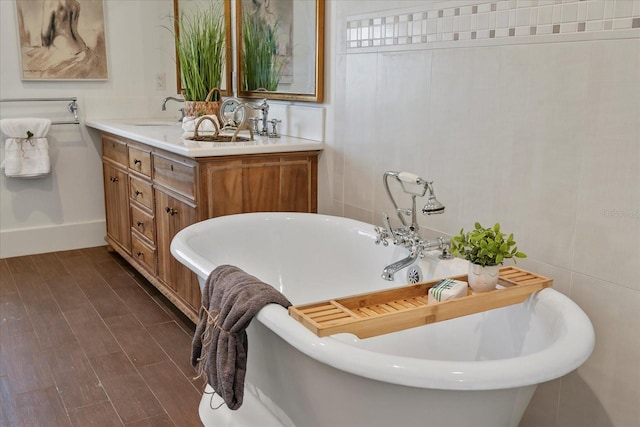 bathroom with hardwood / wood-style floors, oversized vanity, a bathing tub, and dual sinks