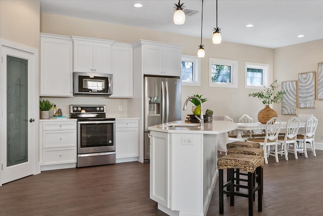 kitchen featuring appliances with stainless steel finishes, pendant lighting, dark wood-type flooring, and white cabinetry