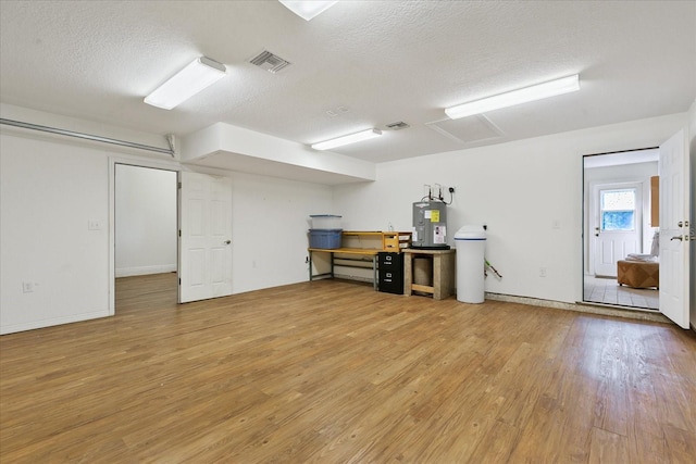 basement featuring a textured ceiling, water heater, and light tile flooring