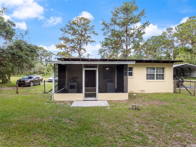 rear view of property featuring a yard, a sunroom, and a carport