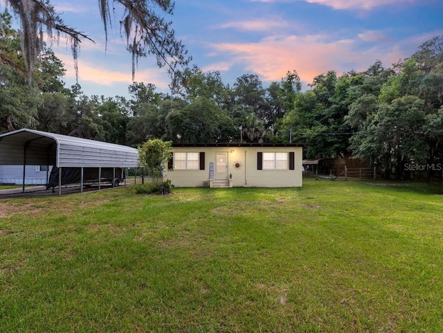 back house at dusk with a lawn and a carport