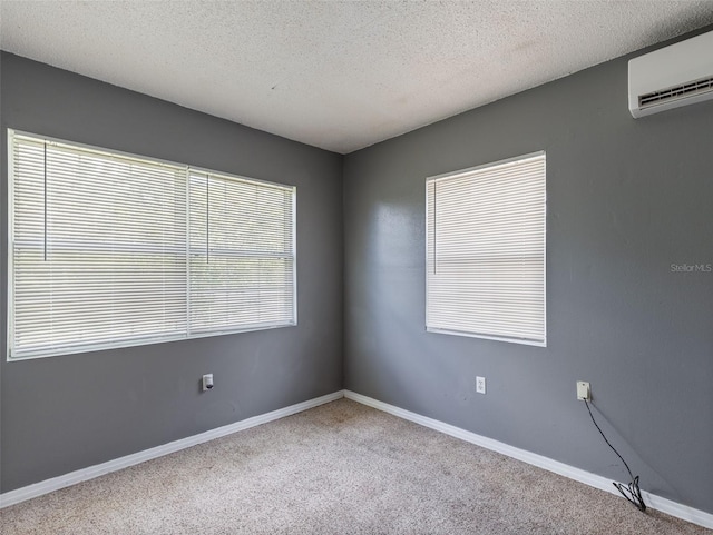 carpeted spare room featuring a wall unit AC and a textured ceiling