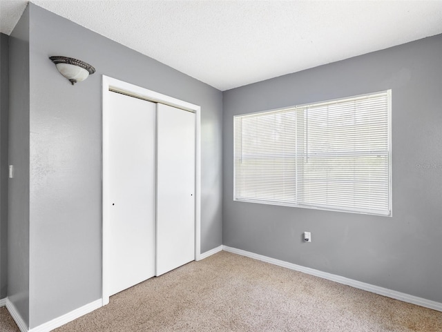 unfurnished bedroom with light colored carpet and a closet