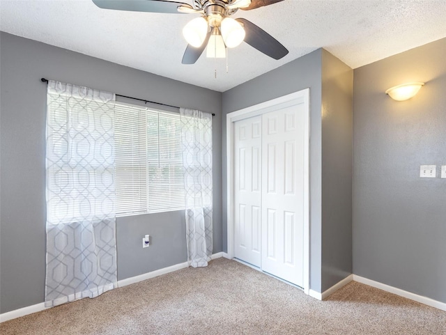 unfurnished bedroom featuring a textured ceiling, a closet, ceiling fan, and carpet flooring