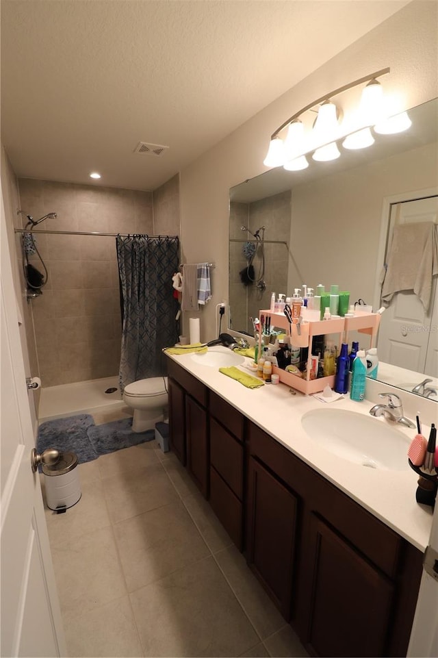 bathroom featuring curtained shower, tile flooring, a textured ceiling, toilet, and double vanity