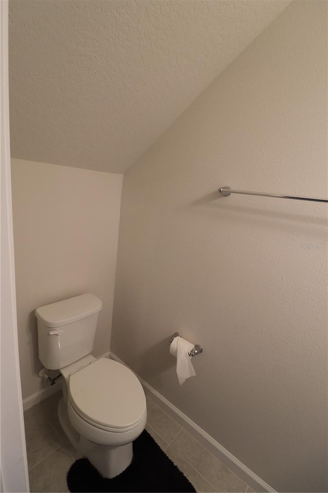 bathroom featuring toilet, tile flooring, and a textured ceiling