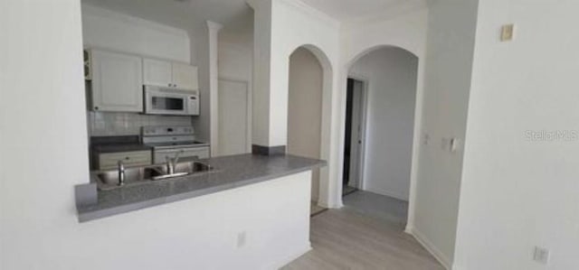 kitchen featuring sink, stove, backsplash, light hardwood / wood-style floors, and white cabinetry