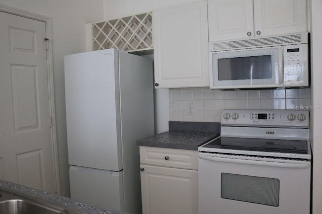 kitchen with backsplash, white appliances, and white cabinetry