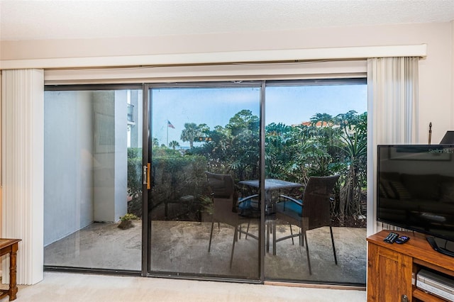 doorway to outside with light carpet, a textured ceiling, and a healthy amount of sunlight