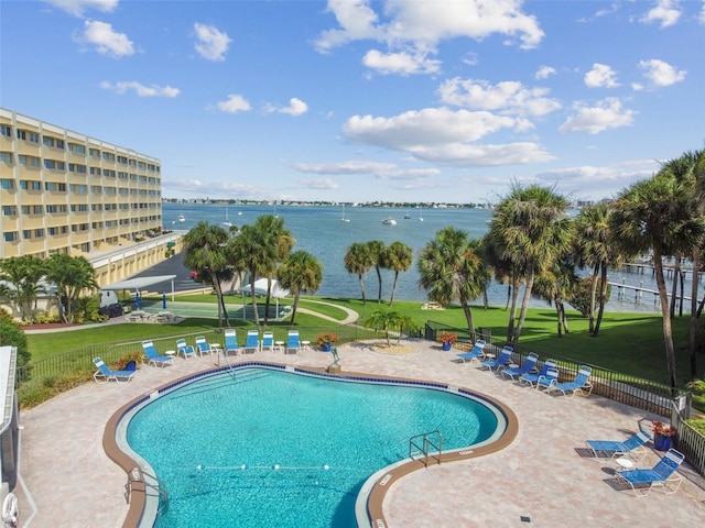 view of swimming pool featuring a lawn, a water view, and a patio area