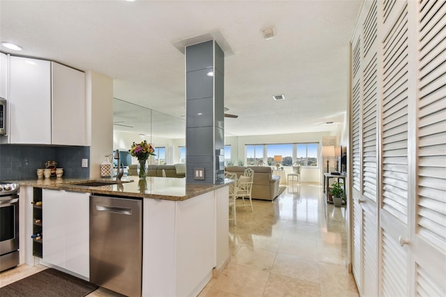 kitchen featuring dark stone counters, decorative backsplash, white cabinets, and appliances with stainless steel finishes