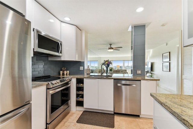 kitchen with light stone countertops, stainless steel appliances, and white cabinets