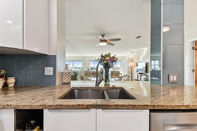 kitchen with tasteful backsplash, sink, light stone counters, and white cabinets