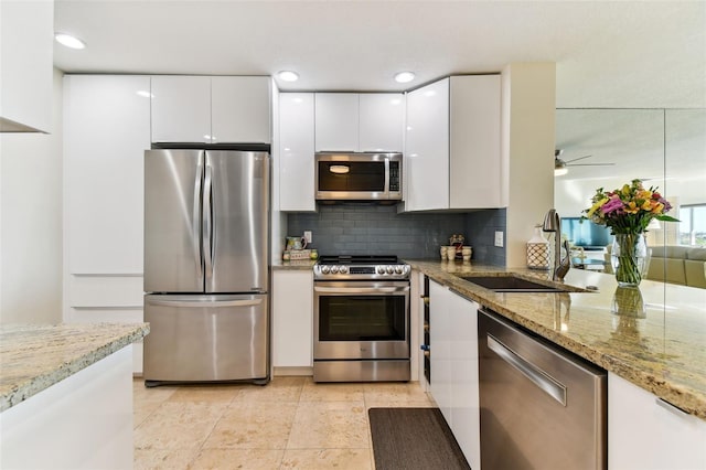 kitchen featuring stainless steel appliances, white cabinets, and light stone counters