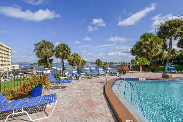 view of swimming pool with a water view and a patio area