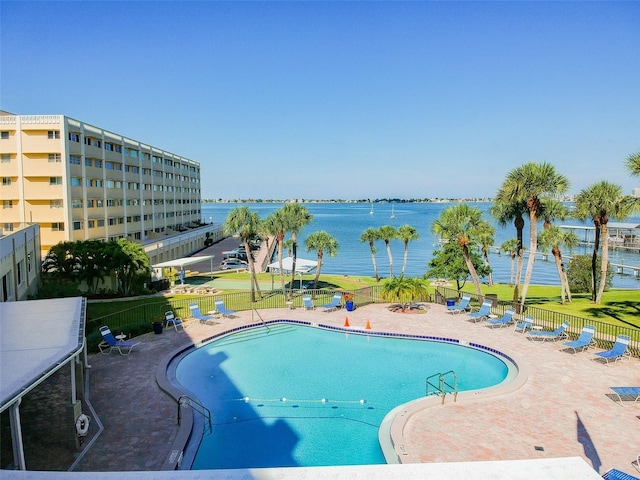 view of pool featuring a lawn, a water view, and a patio area