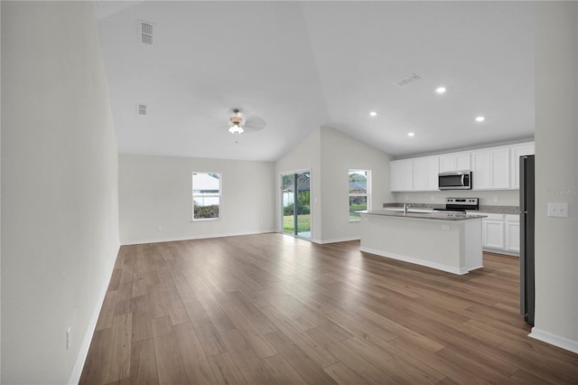 kitchen featuring stainless steel appliances, high vaulted ceiling, hardwood / wood-style flooring, a center island with sink, and white cabinets