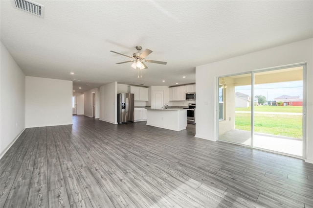 unfurnished living room with sink, ceiling fan, a textured ceiling, and light hardwood / wood-style flooring