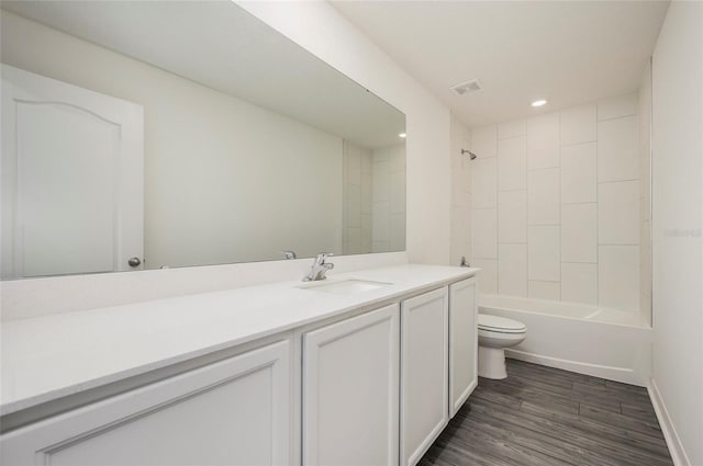 full bathroom featuring vanity, tiled shower / bath combo, wood-type flooring, and toilet