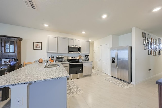 kitchen with kitchen peninsula, stainless steel appliances, light tile patterned flooring, and light stone countertops