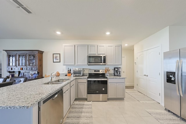 kitchen featuring appliances with stainless steel finishes, sink, light stone counters, kitchen peninsula, and light tile patterned flooring