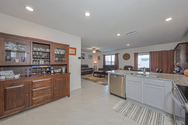 kitchen with light tile patterned floors, sink, dishwasher, ceiling fan, and stove