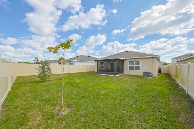 rear view of property with central air condition unit, a sunroom, and a yard