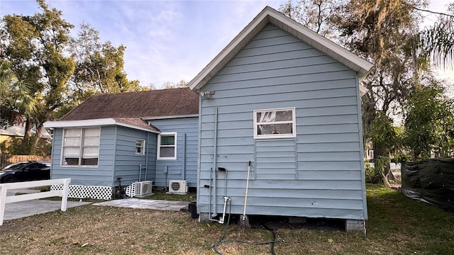 back of property with central AC unit and a lawn