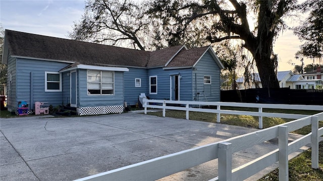 rear view of house with roof with shingles and a fenced front yard