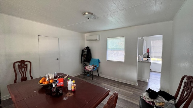 dining space with a wall mounted AC, wood finished floors, and baseboards