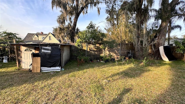 view of yard with an outbuilding, fence, and a storage shed