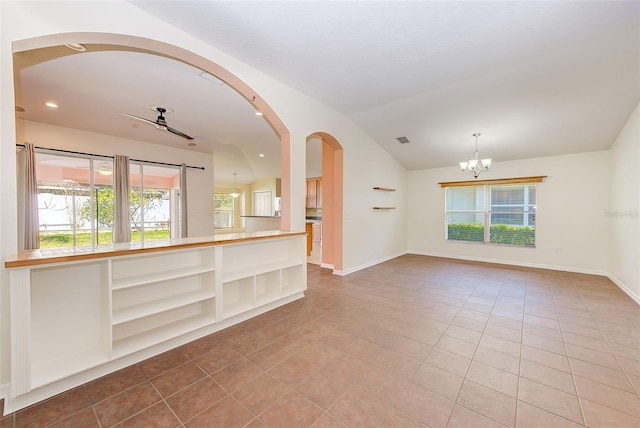 tiled spare room featuring lofted ceiling and a notable chandelier