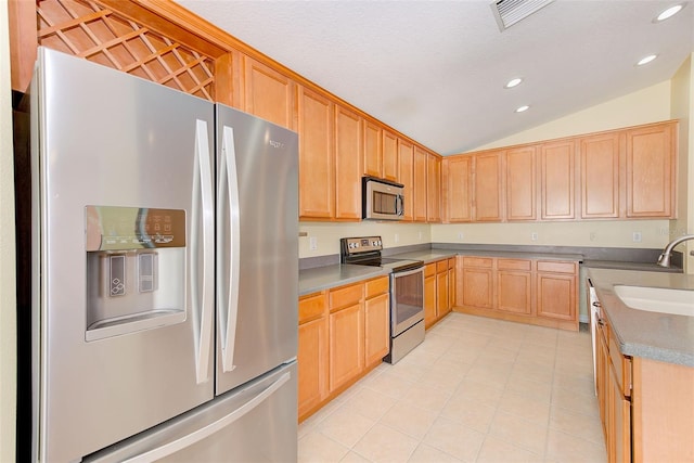 kitchen with light brown cabinets, light tile floors, appliances with stainless steel finishes, lofted ceiling, and sink