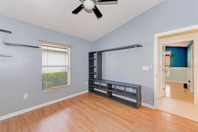 spare room with lofted ceiling, ceiling fan, and light tile floors