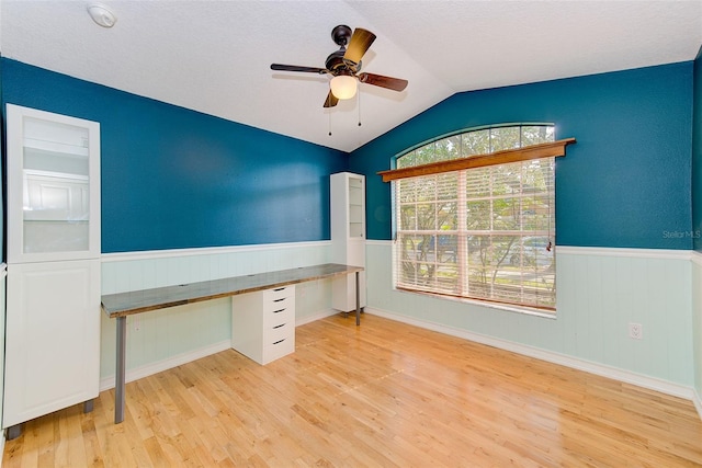 unfurnished office featuring ceiling fan, a healthy amount of sunlight, vaulted ceiling, and light wood-type flooring