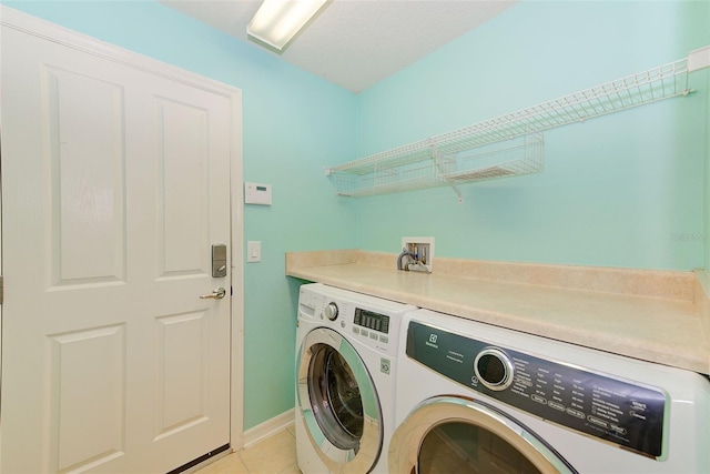 washroom featuring light tile flooring, washer hookup, and washer and clothes dryer