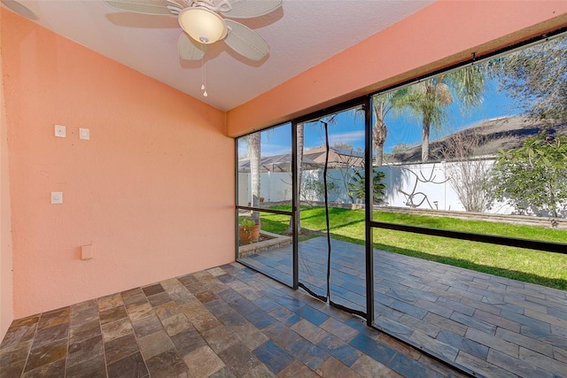 unfurnished sunroom with ceiling fan