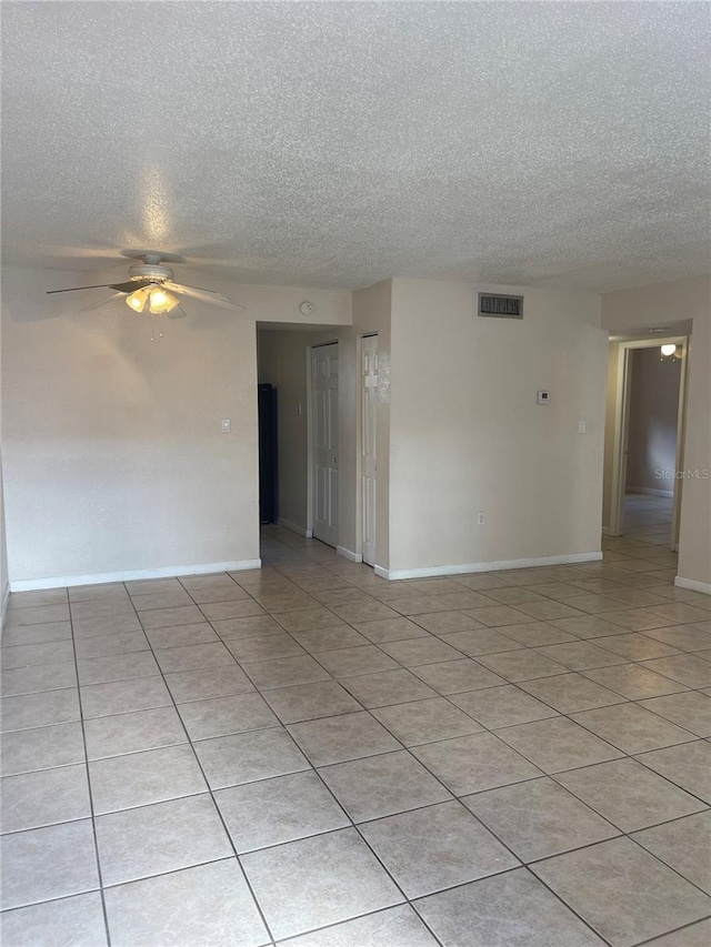 tiled spare room with a textured ceiling and ceiling fan