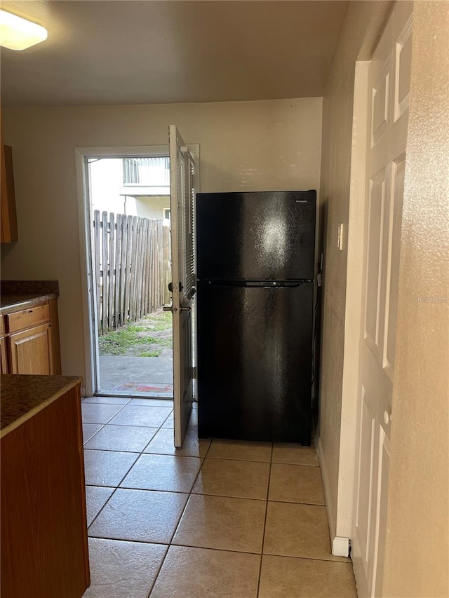 kitchen with black refrigerator and light tile flooring