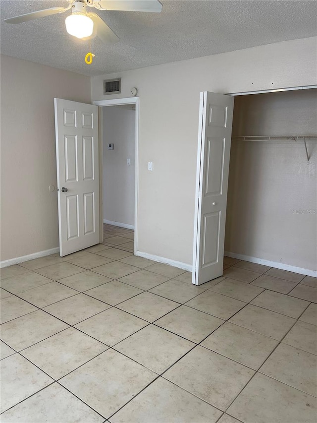 unfurnished bedroom with light tile floors, a closet, ceiling fan, and a textured ceiling