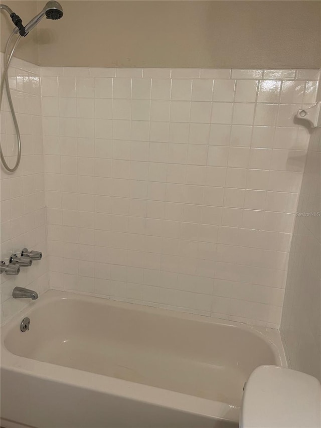 bathroom with tiled shower / bath combo and toilet