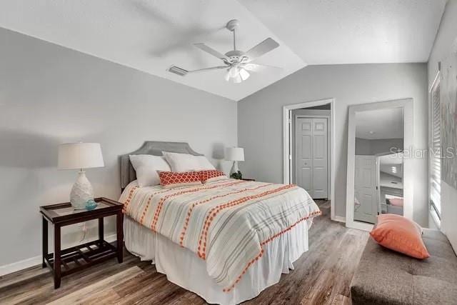 bedroom with a closet, lofted ceiling, dark hardwood / wood-style floors, and ceiling fan