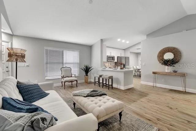 living room featuring lofted ceiling and light hardwood / wood-style floors