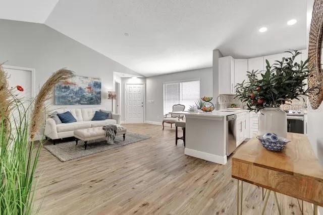 living room featuring lofted ceiling, sink, and light wood-type flooring