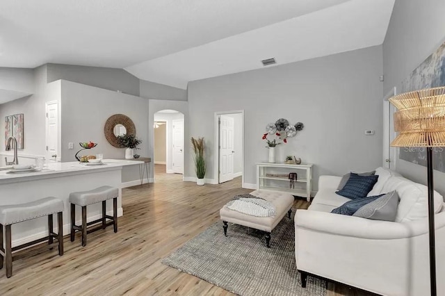 living room featuring light hardwood / wood-style floors, sink, and lofted ceiling