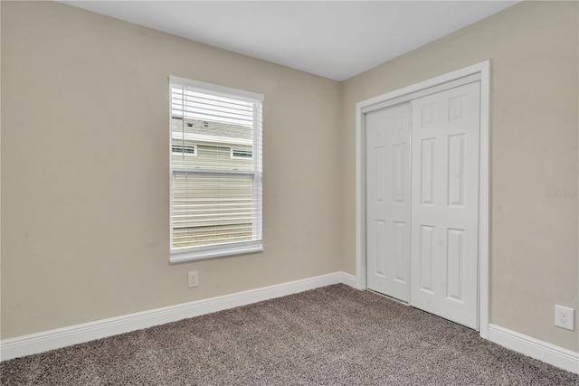 unfurnished bedroom with dark carpet, a closet, and multiple windows